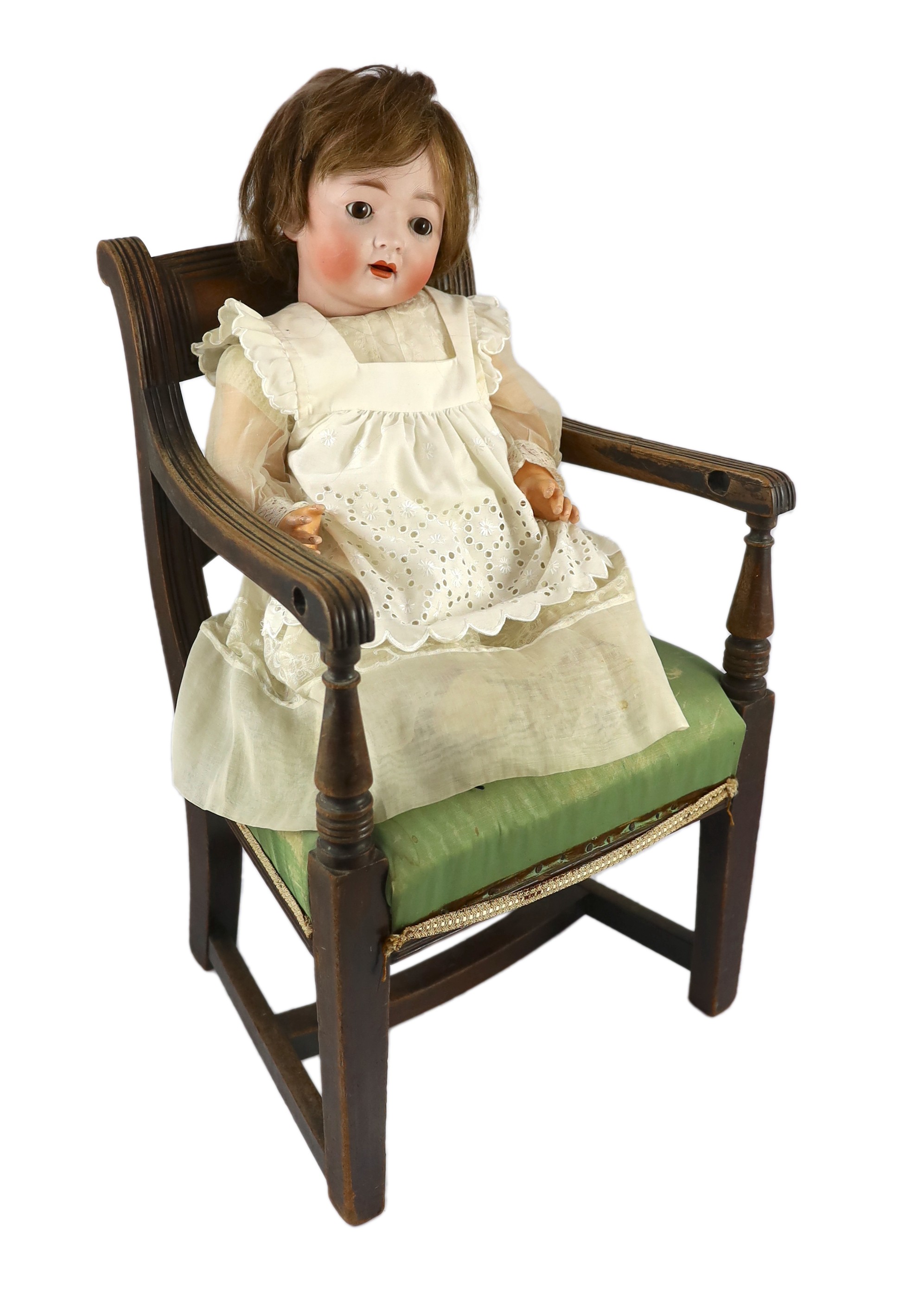 A Kohl and Wengenroth bisque character doll, German, circa 1910, 21in. Please note the chair is for display purposes only.